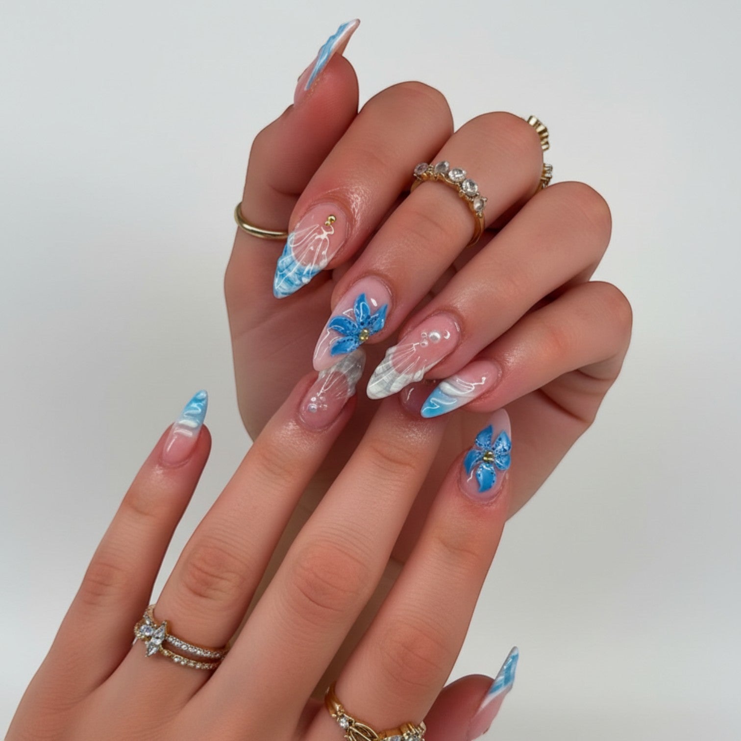 Aura24 press-on nails with blue floral designs and white accents. Almond shape, glossy finish.