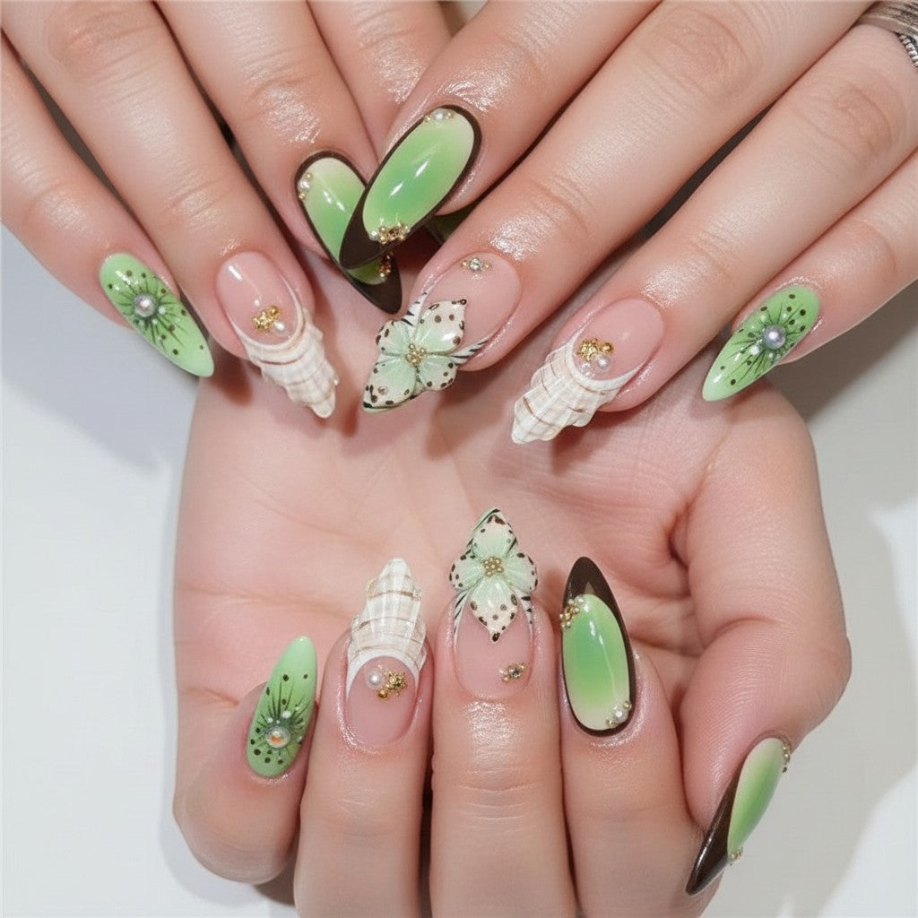 Aura25 press-on nails with green ombre, butterfly, and seashell designs. Features gold accents and pearl details.