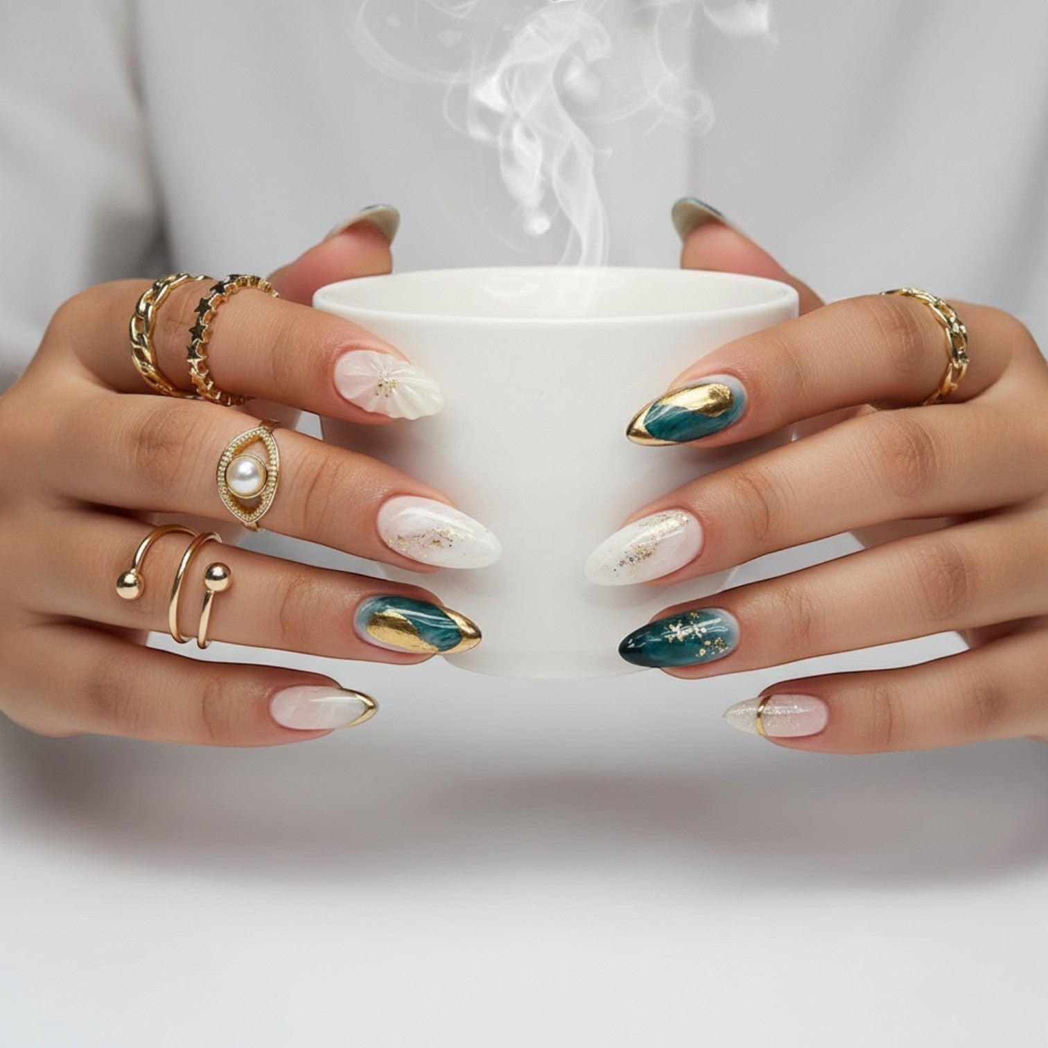 Aurapal almond press-on nails featuring emerald green, off-white marble swirls, and gold leaf accents on hands with rings.