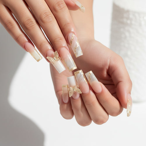 Aura10 press-on nails with white marble, gold foil accents, and 3D gold butterfly charms. Long, square shape.