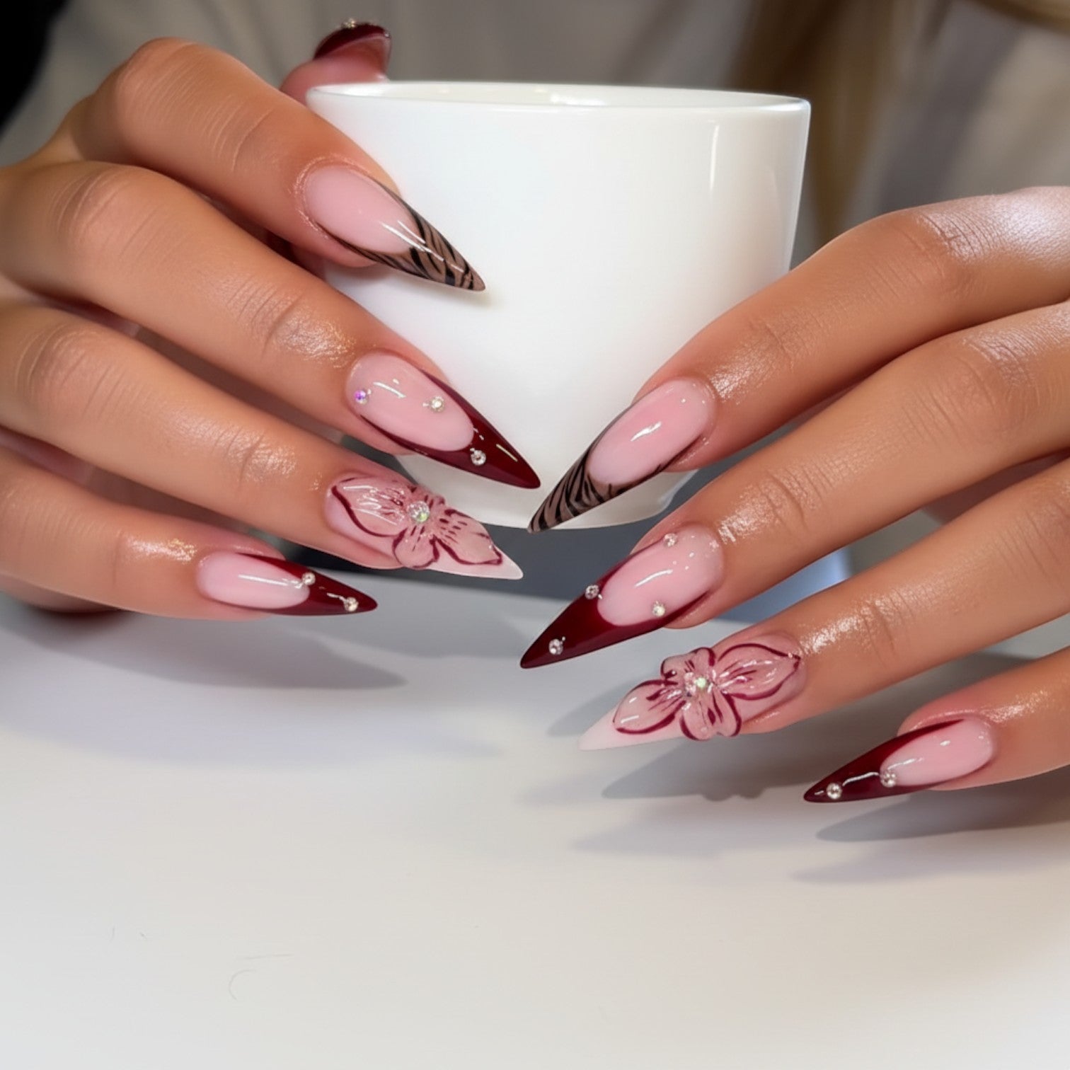 Aura33 stiletto press-on nails with French tips, tiger print, floral designs, and rhinestones. Burgundy and pink.