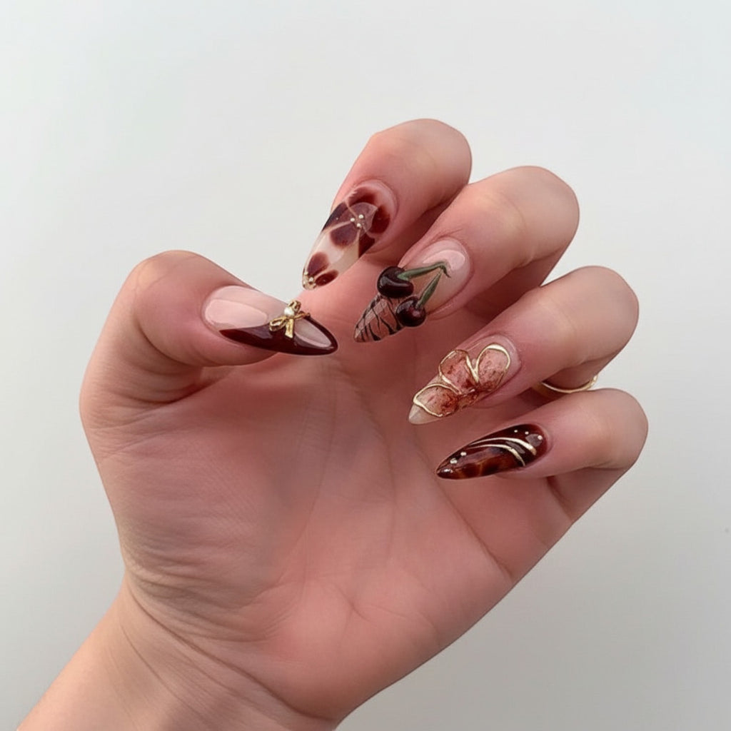 Aurapal Aura23 press-on nails in brown and clear with 3D cherry, bow, and flower charms. Almond shape.
