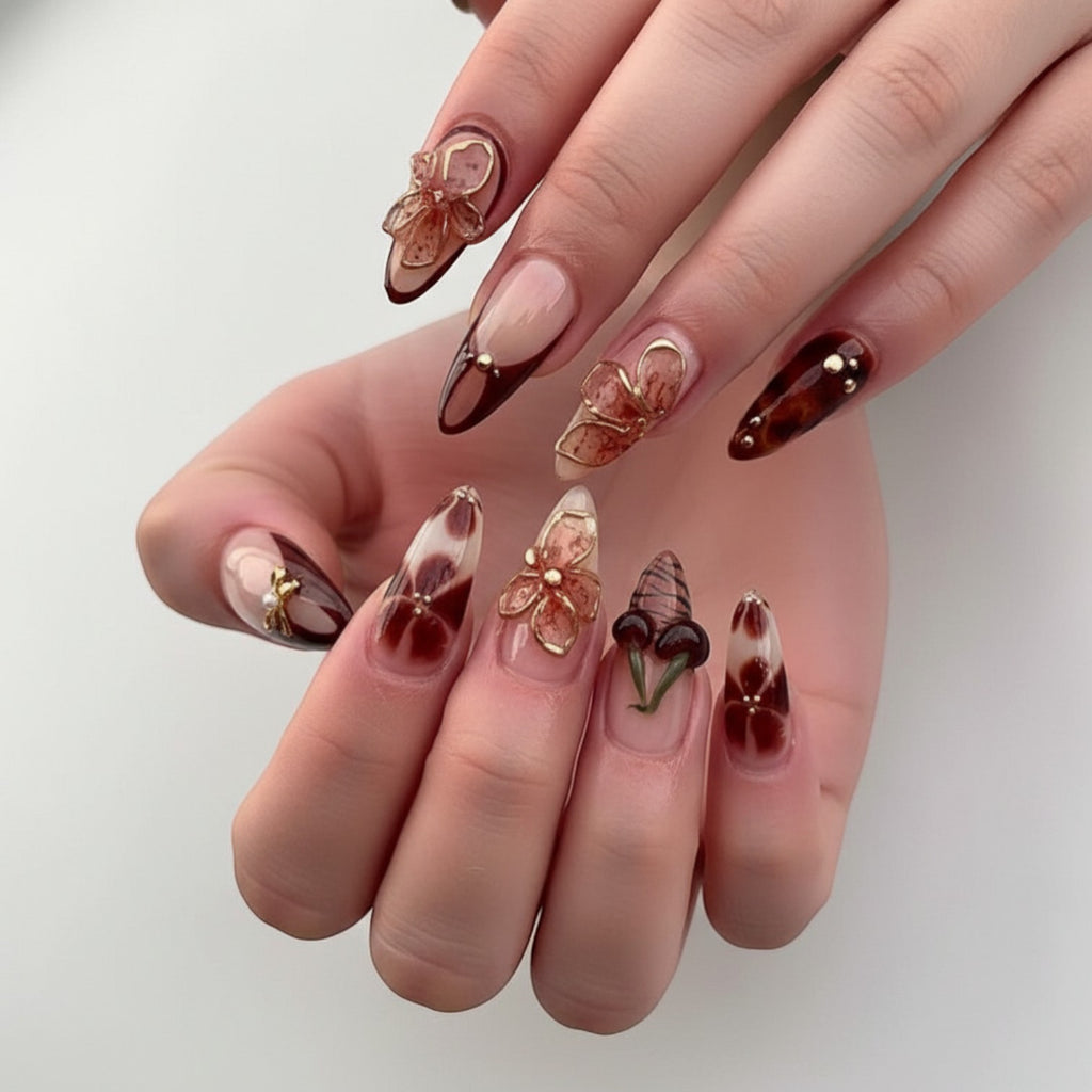 Aurapal Aura23 press-on nails in brown and clear with cherry, bow, and flower charms. Almond shape.