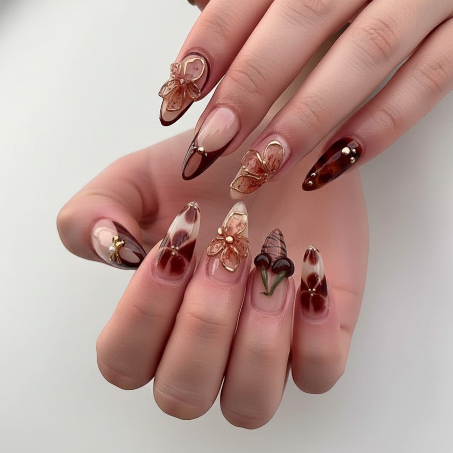 Aurapal Aura23 press-on nails in brown and clear with cherry, bow, and flower charms. Almond shape.