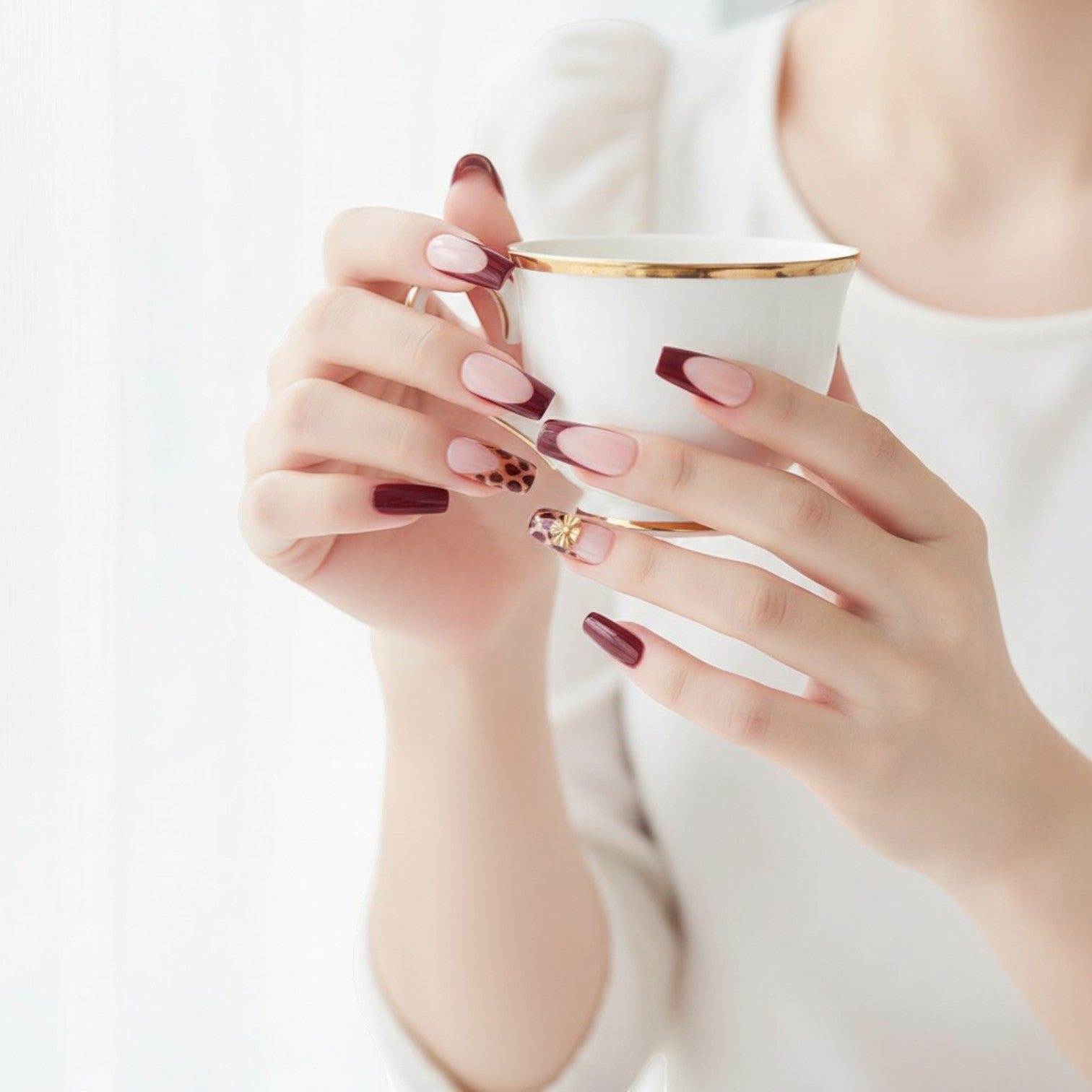 Press Aura57 press-on nails in burgundy, gold, and leopard print with gold bead and cross embellishments.
