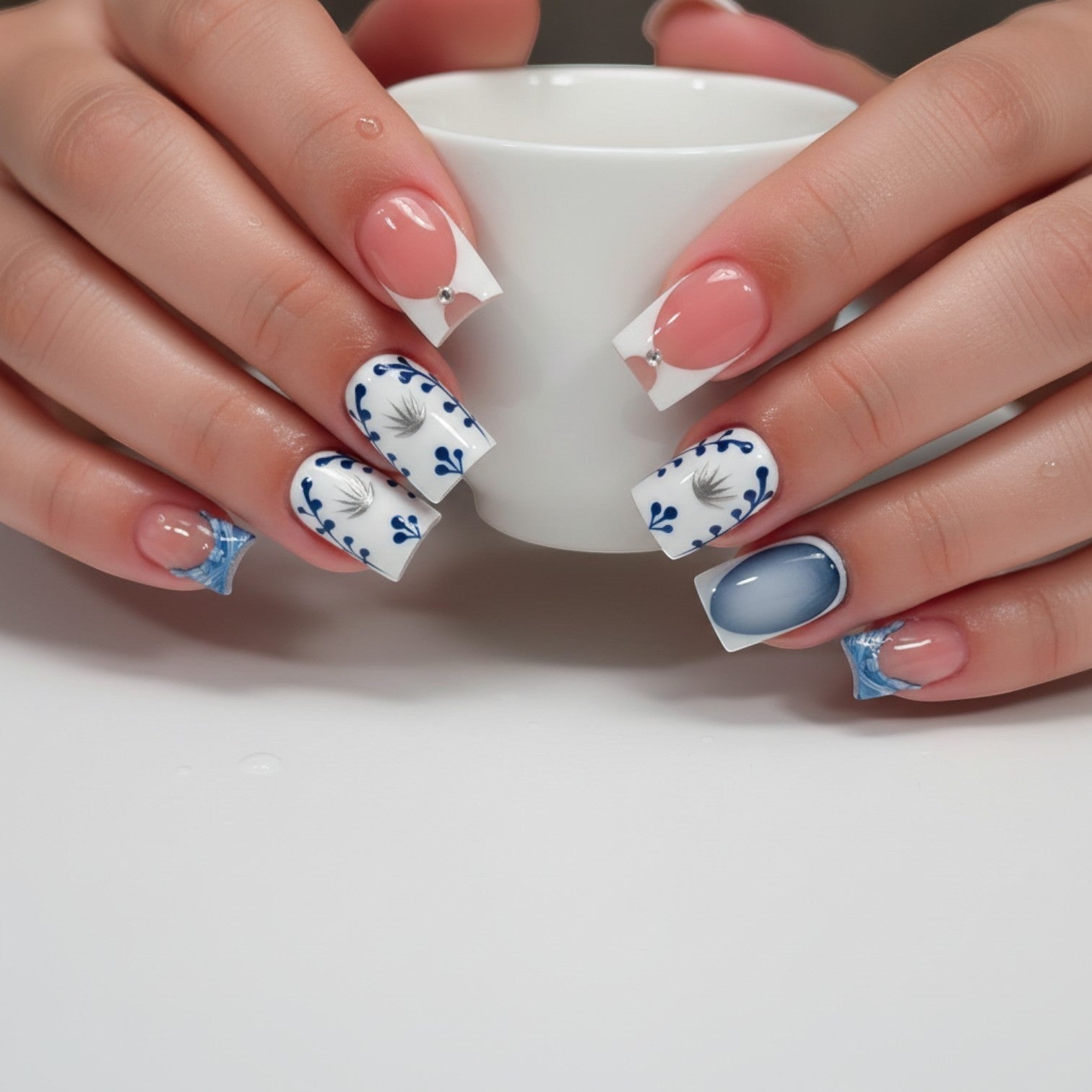 Aurapal press-on nails featuring a French-tip, blue floral pattern, and navy ombre design on a square nail shape.