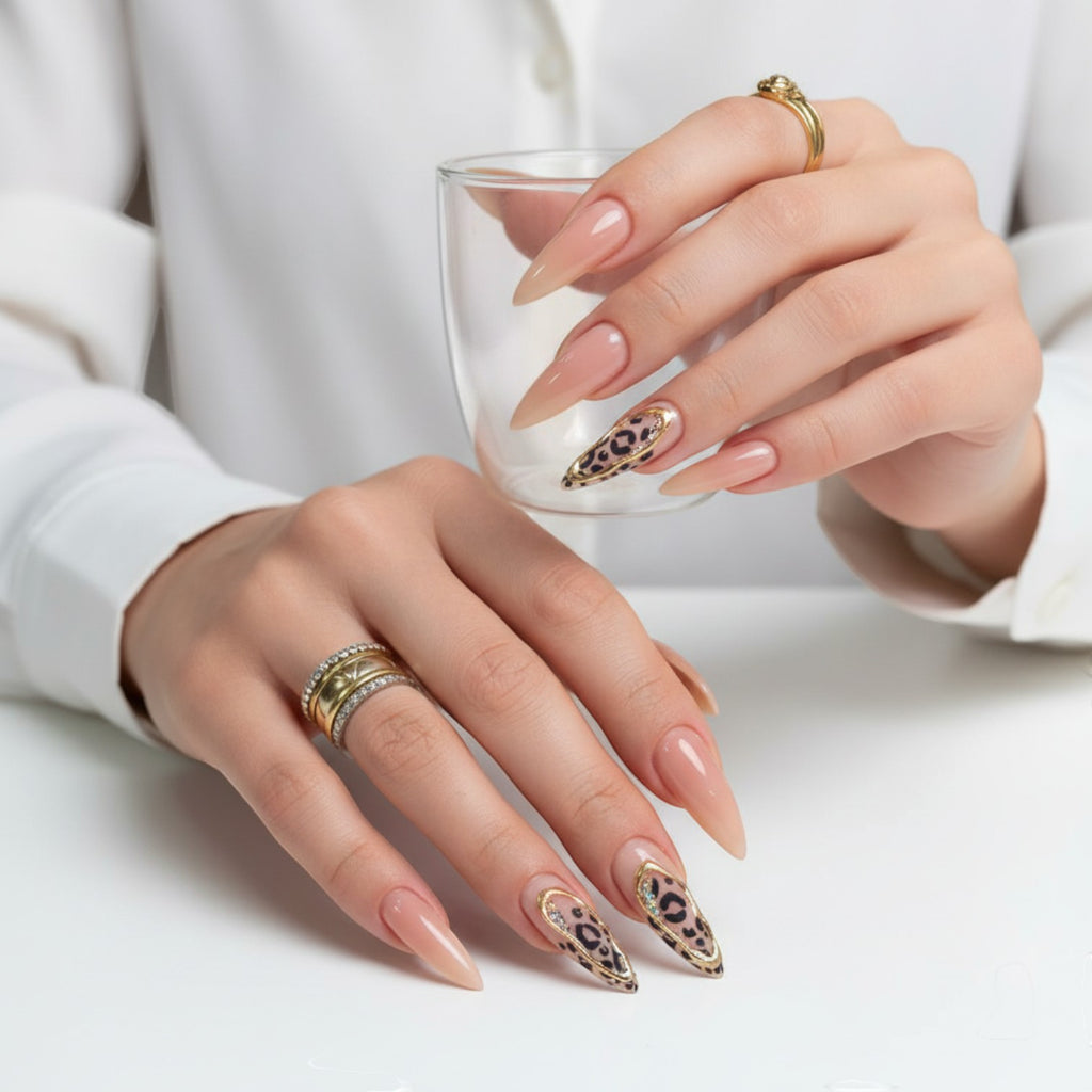 AuraPress Aura39 stiletto press-on nails with leopard print, gold trim, and rhinestones. Nude base.
