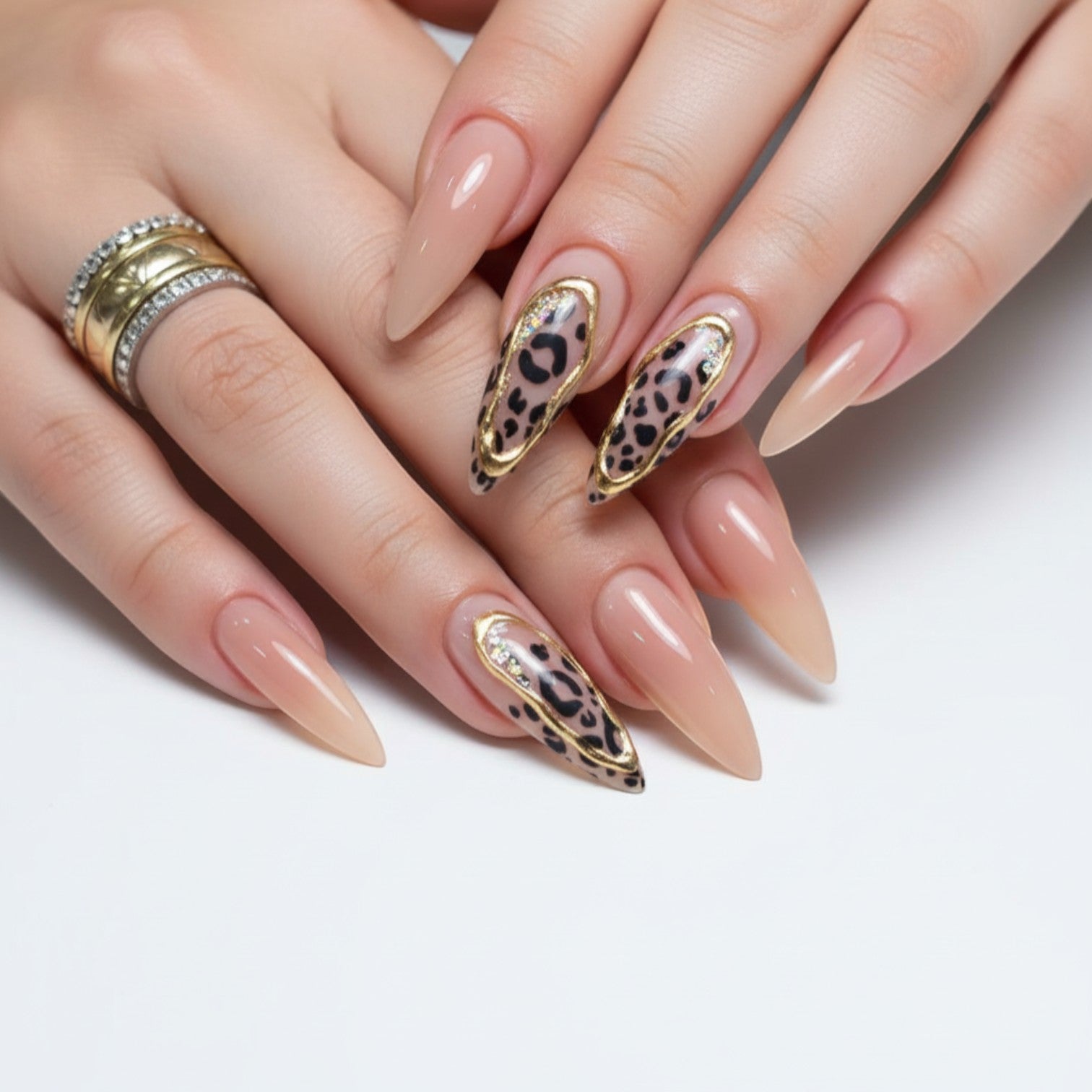 AuraPress Aura39 stiletto press-on nails with leopard print, gold trim, and rhinestones. Nude base with glossy finish.