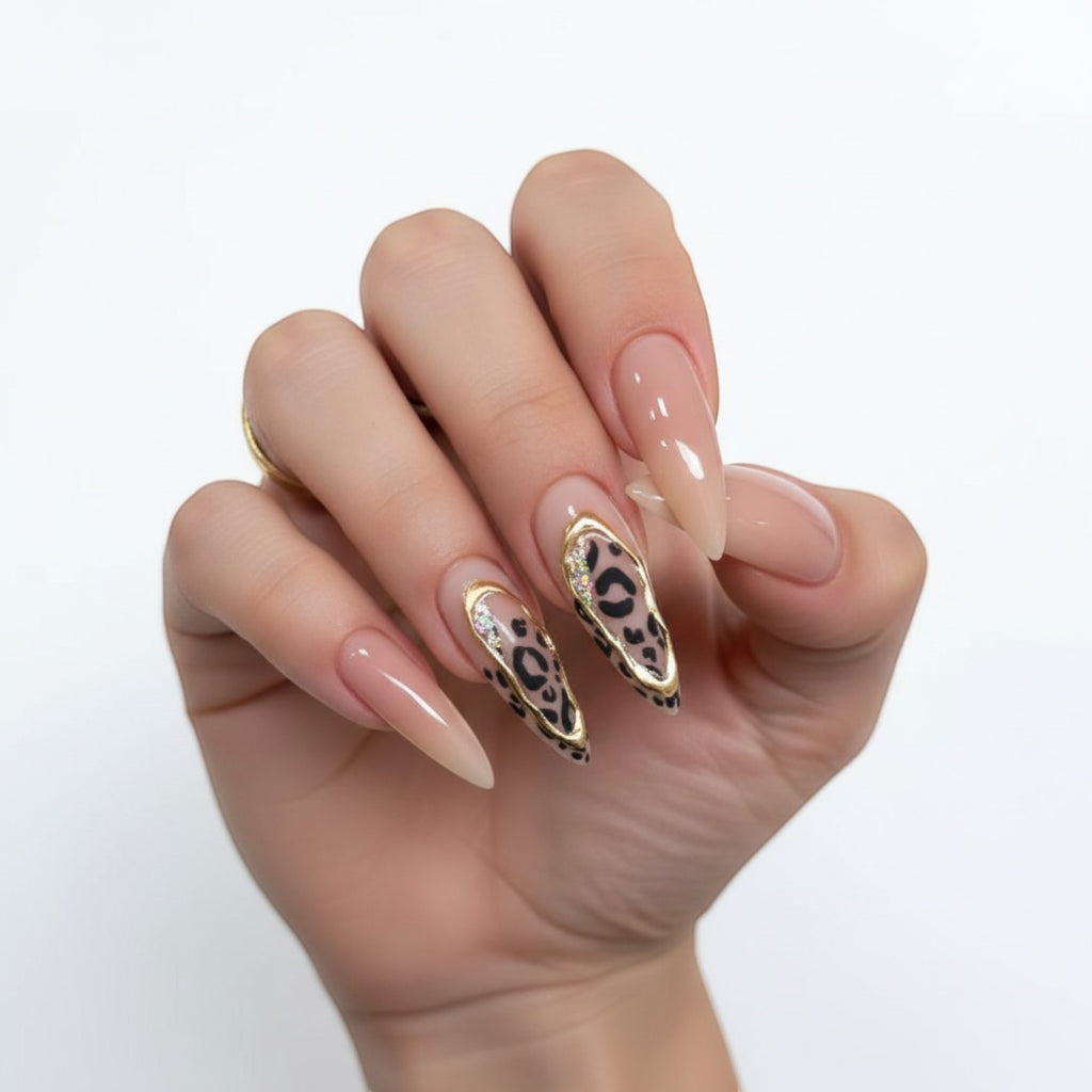 AuraPress Aura39 stiletto press-on nails with leopard print, gold trim, and rhinestones. Nude base.