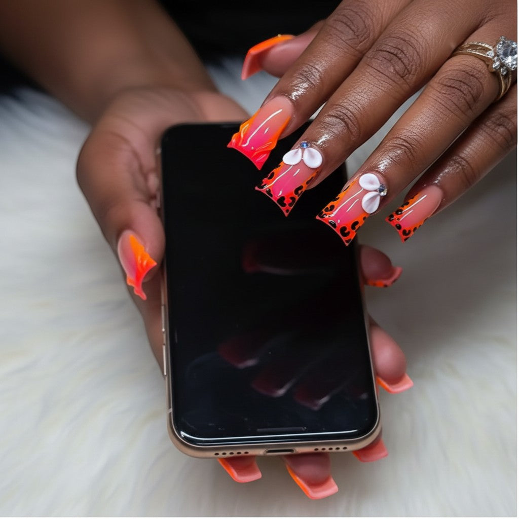 AuraPal Aura63 press-on nails with neon orange French tips, leopard print, and 3D flower accents.
