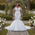 Aurapal off-the-shoulder mermaid wedding dress with lace bodice, illusion sleeves, and tulle skirt in a garden.