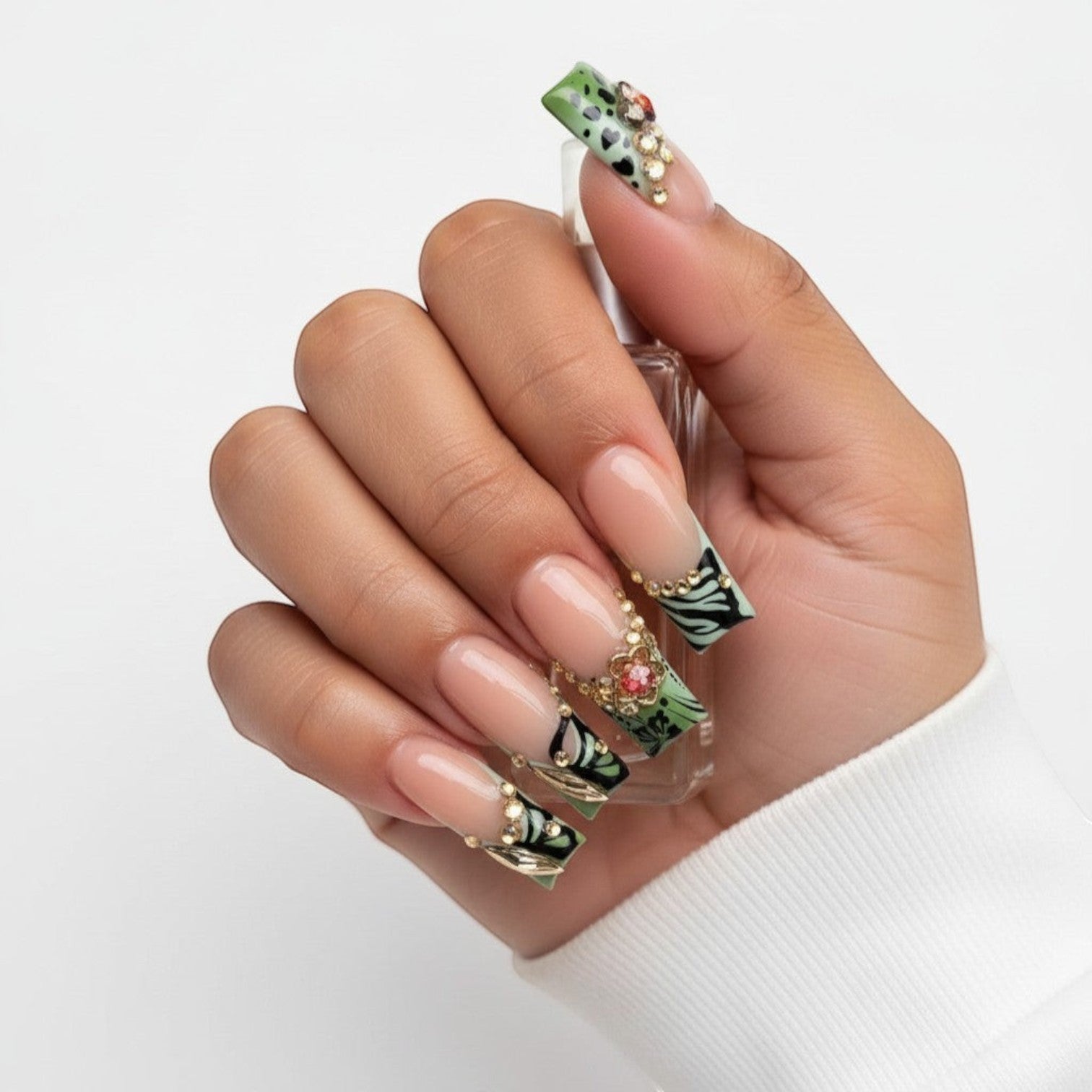 Aura20 press-on nails with green, black, and nude French tips, adorned with rhinestones and butterfly designs.