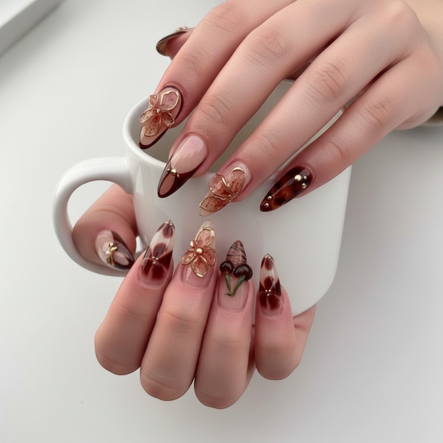 Aurapal Press Aura23 press-on nails with 3D floral and cherry charms, tortoise shell, and marble designs in brown and nude.
