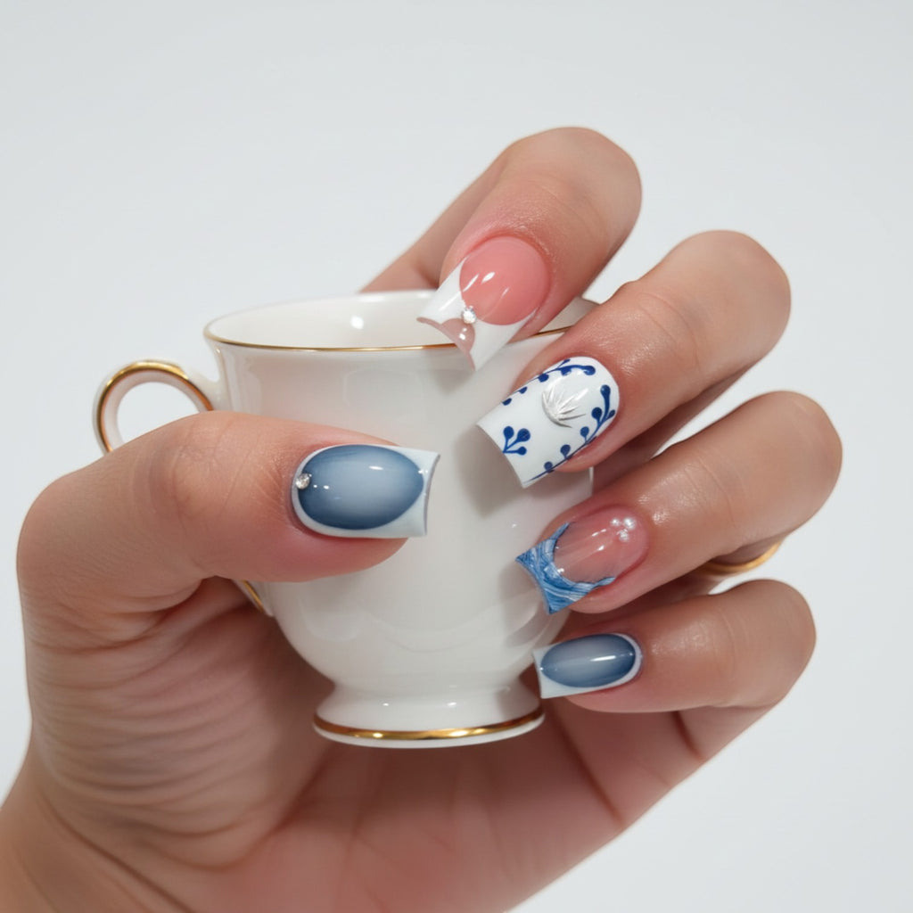 Press Aura55 French tip press-on nails with blue floral design, silver accents, and rhinestones. Pink and blue ombre.