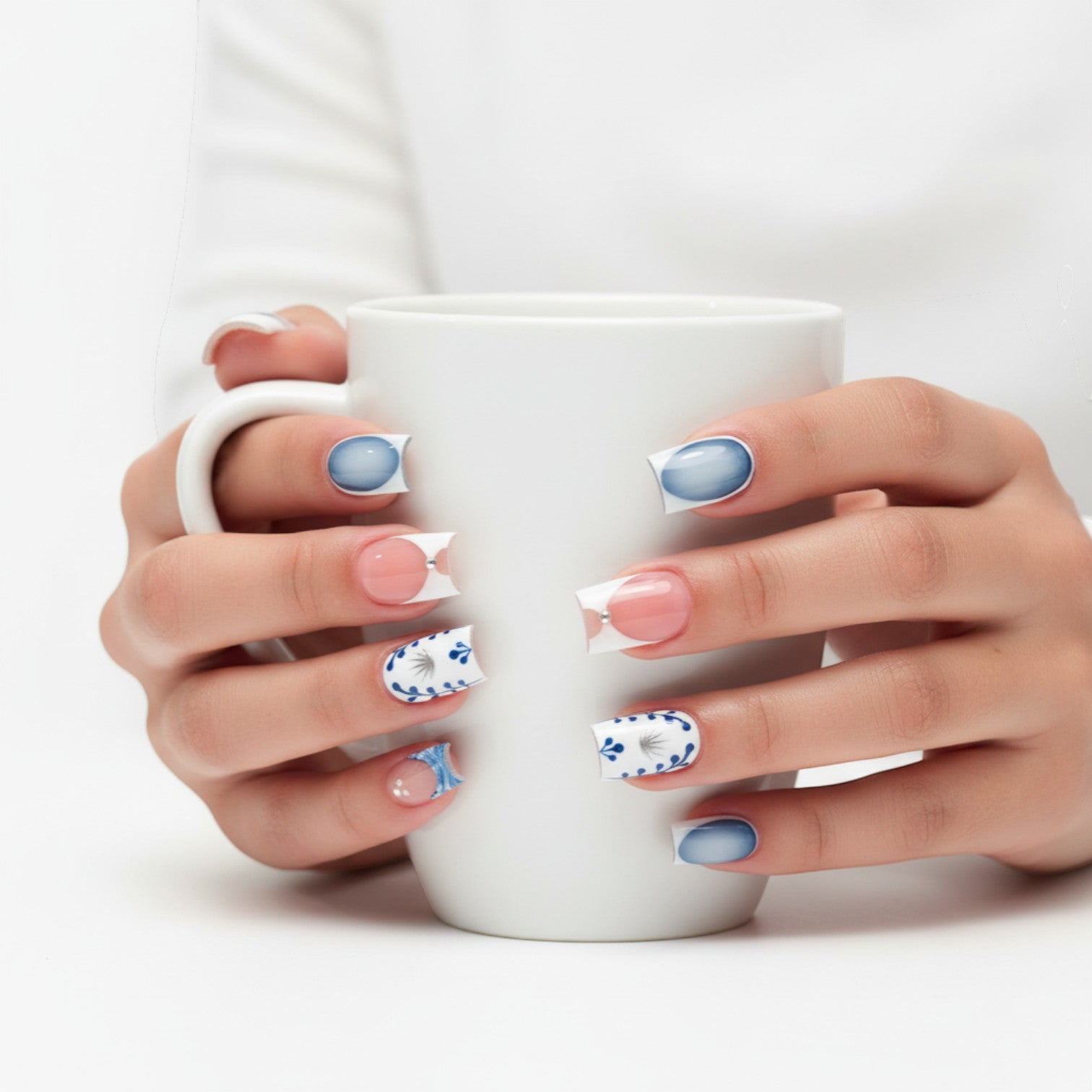 Press Aura55 French tip press-on nails with blue floral design, silver accents, and rhinestones. Pink and blue ombre.