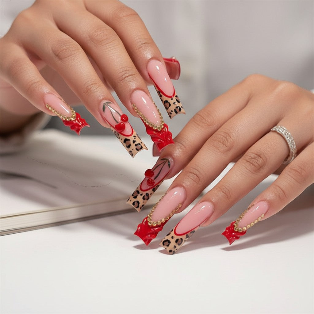 AuraPress Aura62 press-on nails with pink French tips, leopard print, red cherry charms, and gold rhinestone accents.